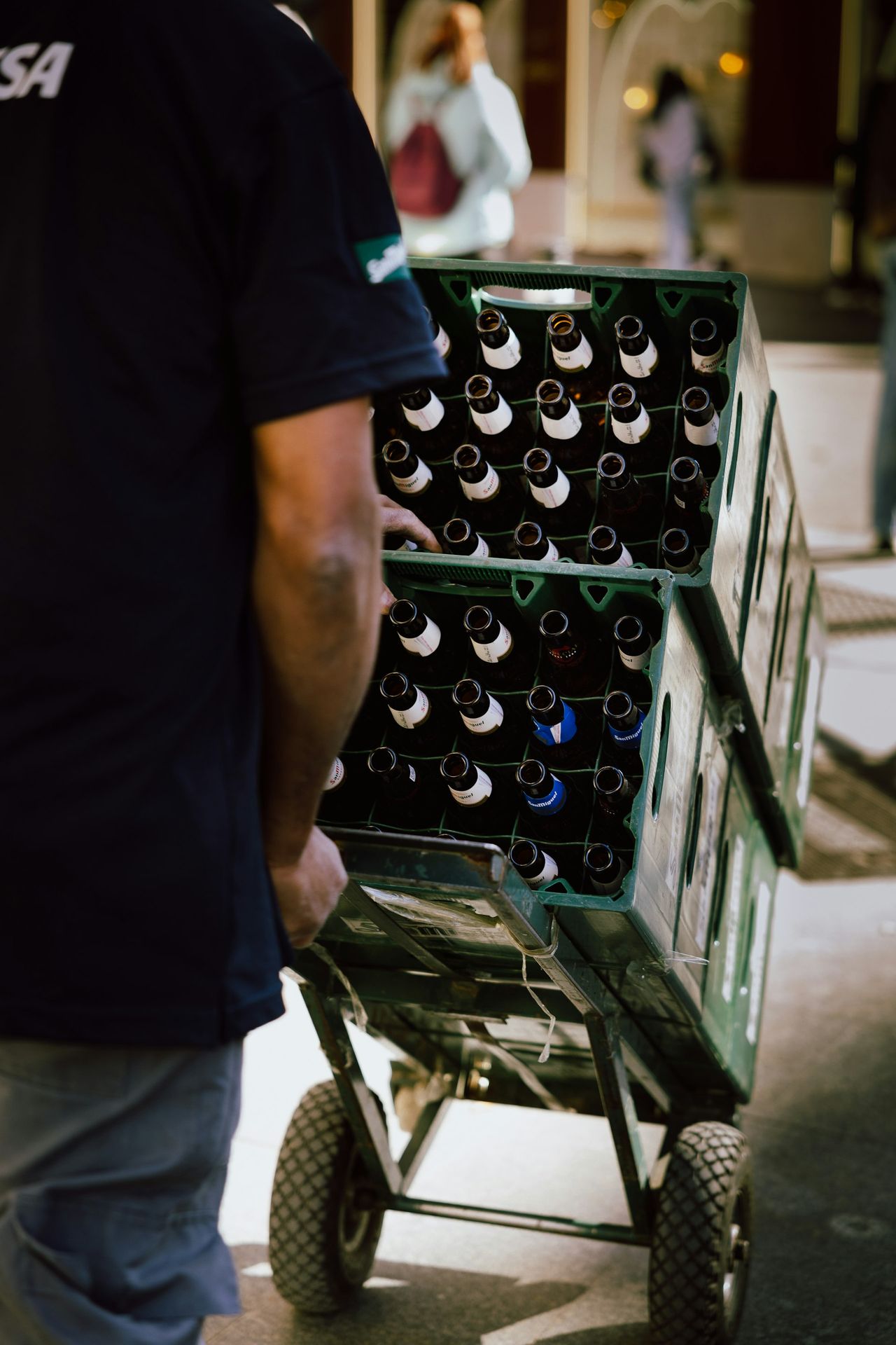 A man pushing a cart full of beer bottles